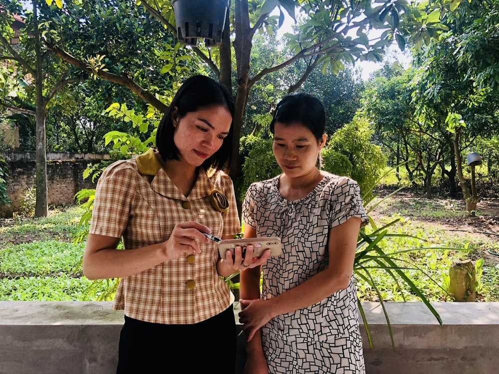 Cán bộ lao động, thương binh và xã hội xã Đông Ninh hướng dẫn người dân sử dụng mạng internet để tìm kiếm thông tin về chính sách giảm nghèo