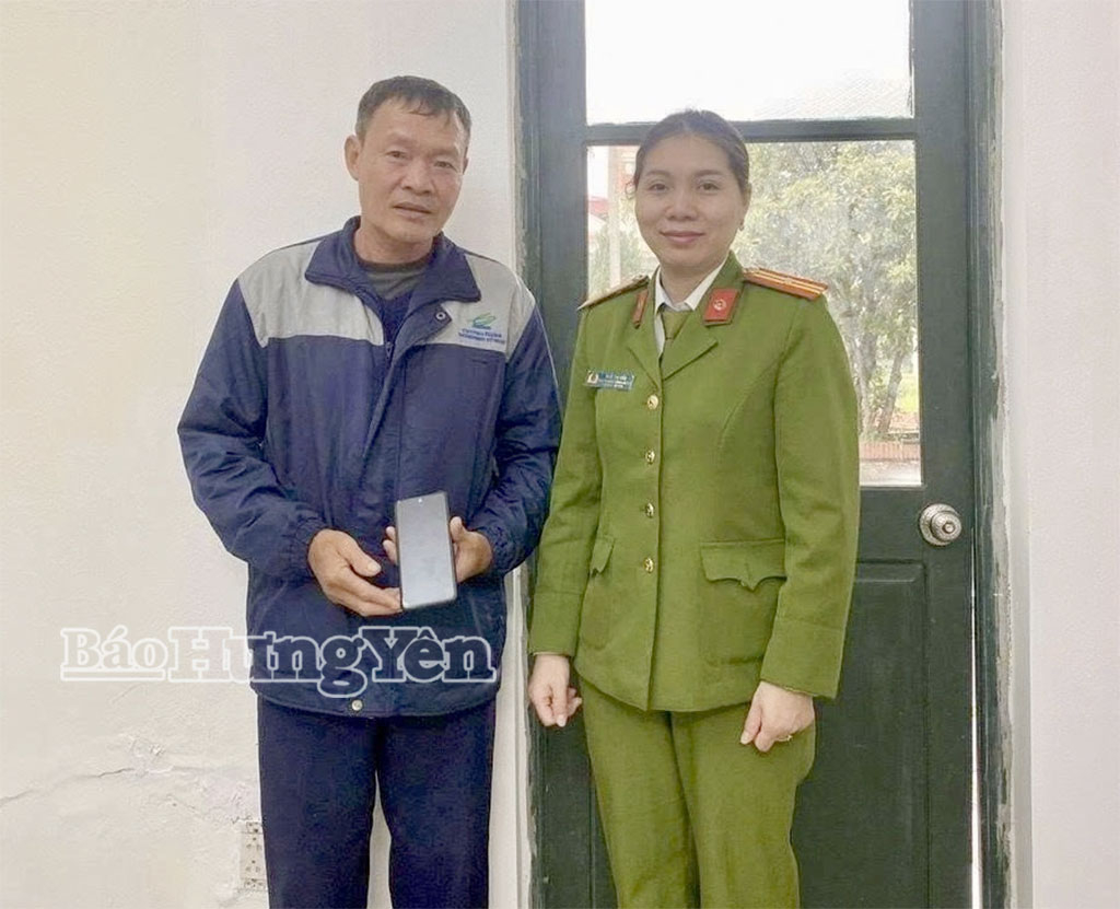 Cán bộ Công an xã Ân Thi trao trả chiếc điện thoại do 2 học sinh Trường THCS Phạm Huy Thông nhặt được cho anh Trương Văn Ban. 